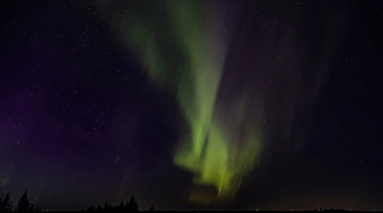 Green northern lights over a dark northern landscape